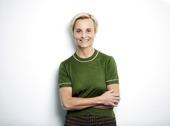 A woman in a green shirt smiles with crossed arms against a white background, exuding a peppermint freshness.
